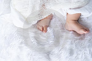 Cute newborn baby foot girl in white blanket onÃ‚Â nurseryÃ‚Â bed.AdorableÃ‚Â new born child people Family.